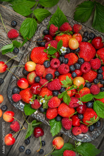 Many different ripe berries strawberries, raspberries, blueberries, cherries, on an old dish and a wooden background. View from above