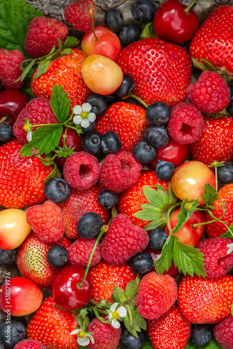 Many different ripe berries strawberries, raspberries, blueberries, sweet cherries as background texture. Flat lay, top view