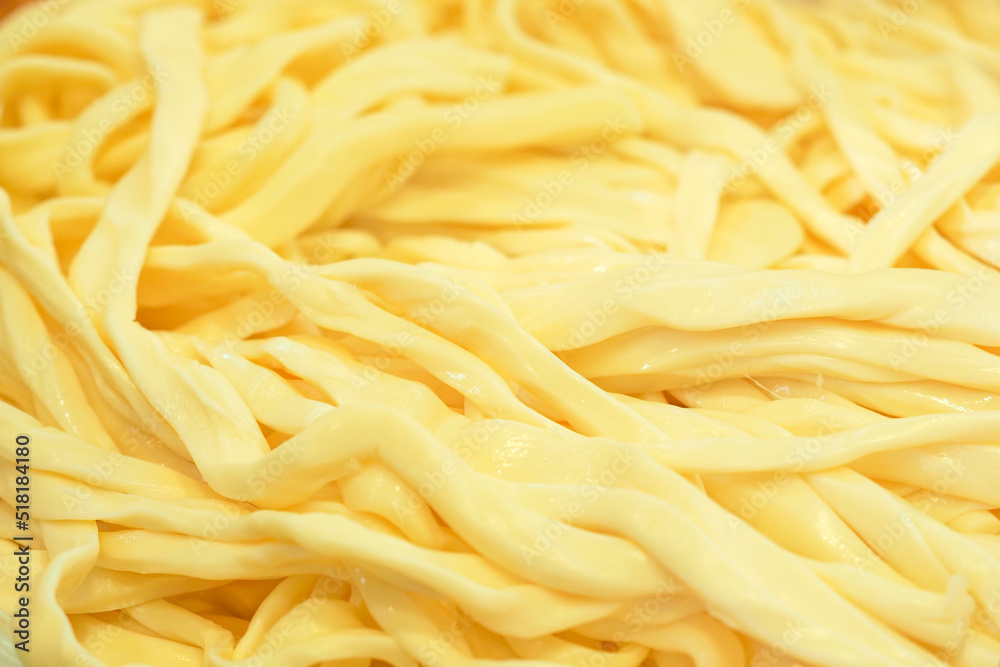 Soft, creamy chechil close-up background. Texture of cheese chechil. Chechil or chechili is an Armenian brined string cheese and is produced in the form of dense strings Soft, creamy chechil close-up background. Texture of cheese chechil. Chechil or chechili is an Armenian brined string cheese and is produced in the form of dense strings