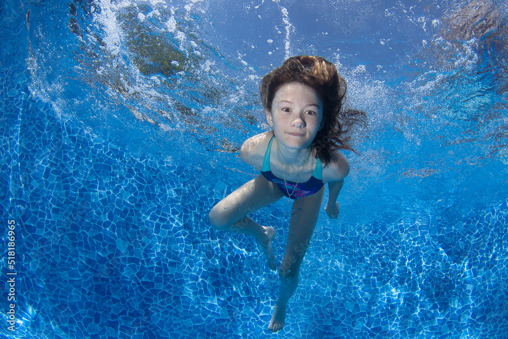 Young girl swims underwater in the pool.