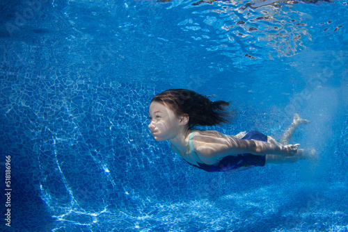 Young girl swims underwater in the pool.