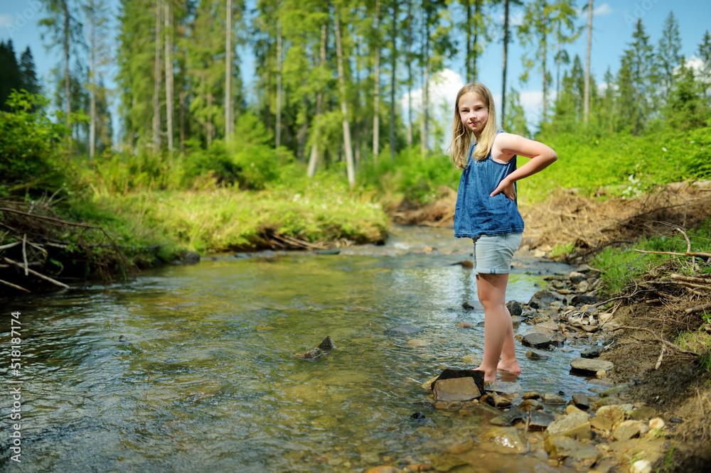Young girl near cold shallow stream winding through majestic pine trees of Tatra mountain range near Zakopane, Poland. Young girl near cold shallow stream winding through majestic pine trees of Tatra mountain range near Zakopane, Poland.