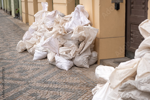 Big white reusable recycling package, filled bags on the city street, piled up in a big pile on a paving stones.