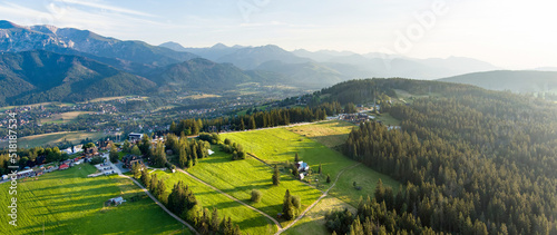 Fototapeta Naklejka Na Ścianę i Meble -  Aerial view of Zakopane town underneath Tatra Mountains taken from the Gubalowka mountain range. High mountains and green hills in summer or spring.