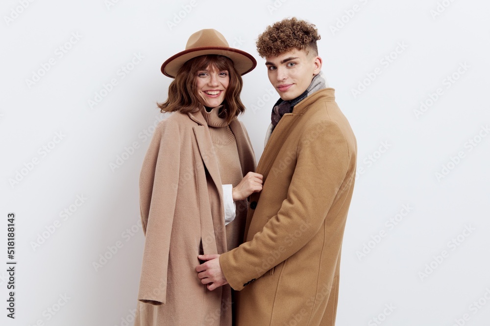 a sweet, beautiful, loving couple stands on a white background in stylish autumn clothes, gently cuddling up to each other and both look into the camera