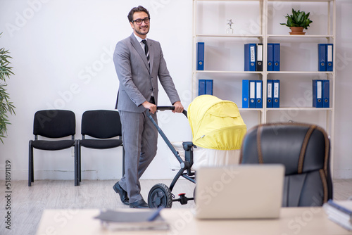 Young male employee looking after new born at workplace