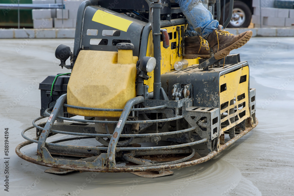 Workers are using concrete polishing machines for cement after pouring concrete on foundation floor in construction site