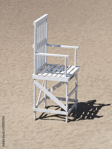 Big white chair on sandy beach.