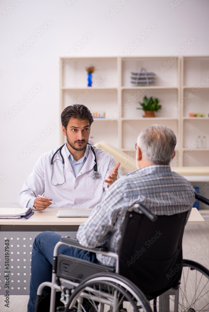 Fototapeta premium Old man in wheelchair visiting young male doctor