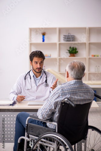 Old man in wheelchair visiting young male doctor