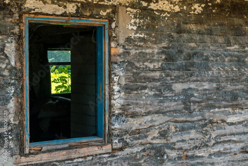 An old wooden uninhabited house. A small house in the village with a sunken roof and walls overgrown with moss. Destroyed housing after the cataclysm and poverty in Russia.