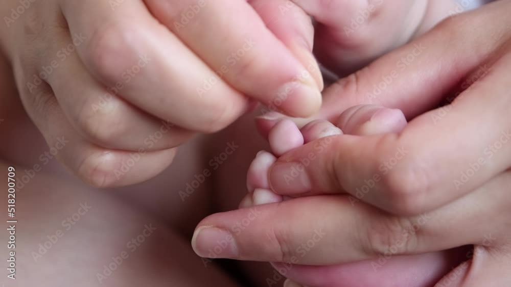 Mother hands are trimming baby foot nails Mother hands are trimming baby foot nails