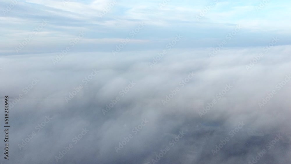 Aerial drone view flight over above fog mist and roofs of buildings in city and under white clouds in the sky. Abstract natural background. Cloudy weather. Atmosphere. Top view fog cloudy movement Aerial drone view flight over above fog mist and roofs of buildings in city and under white clouds in the sky. Abstract natural background. Cloudy weather. Atmosphere. Top view fog cloudy movement