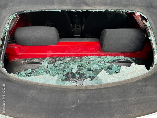 Close up of car accident smashed rear heated glass window on mohair black soft top convertible VW roof with view through hole to automobile interior and back seats with accident shattered pieces cill 