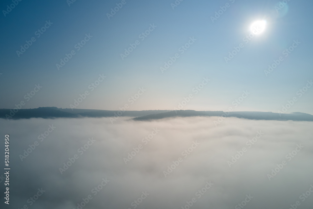 Aerial view from high altitude of earth covered with white puffy cumulus clouds on sunny day