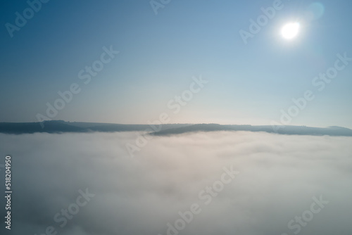 Aerial view from high altitude of earth covered with white puffy cumulus clouds on sunny day