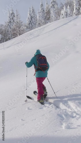 DRONE Fit Caucasian woman observes the beautiful snow covered nature while crossing the wintry landscape during ski touring trip to Bohinj. Active female tourist hikes along a hill while splitboarding
