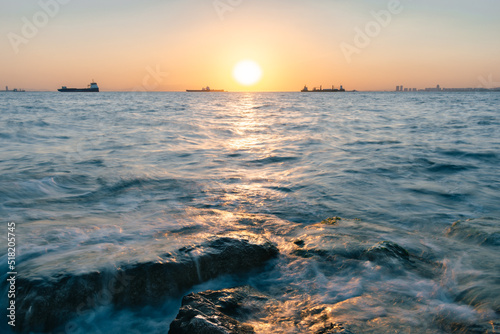 Beautiful seascape at the sunset with creamy sea and stones in the foreground.