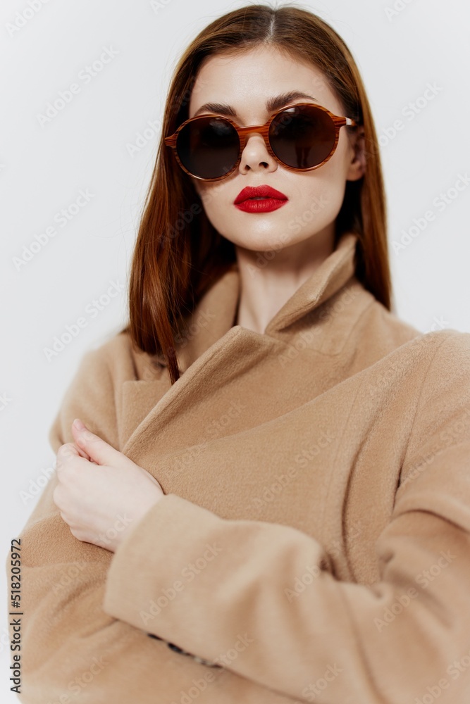 An elegant young woman in glasses and a coat poses for a clothing catalog on a white background. Concept Fashion An elegant young woman in glasses and a coat poses for a clothing catalog on a white background. Concept Fashion