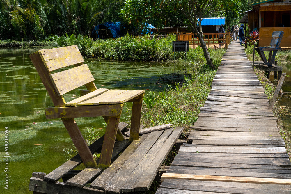 Wooden benches by the lake and wooden plank paths in summer. Wooden bench in the garden