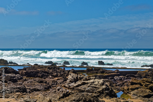 Rock pool with large breakers and cloudy sky