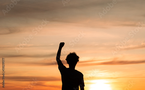 Silhouette of a man feeling strong and determined to overcome life's challenges with sunset in the background