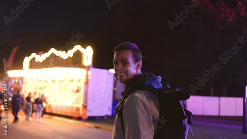 short haired man walking around at a fun fair at a fun fair looking into the camera and smiles photo