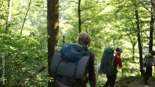 3 guys walking trough a forrest in Luxembourg with huge packpacks photo