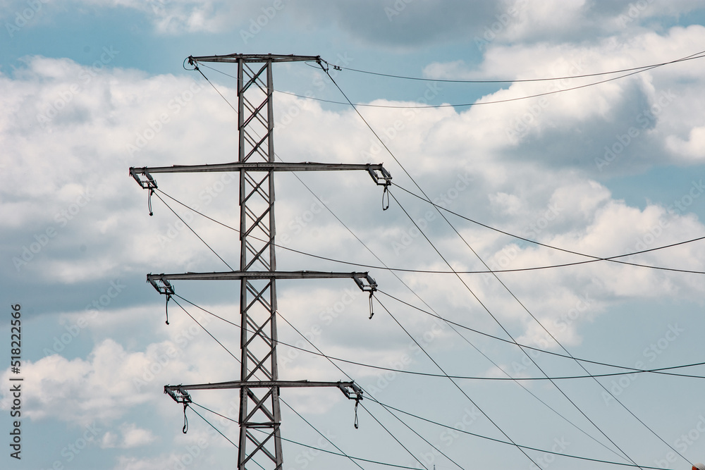 Thin metal pylon with wires connected against a cloudy sky Thin metal pylon with wires connected against a cloudy sky