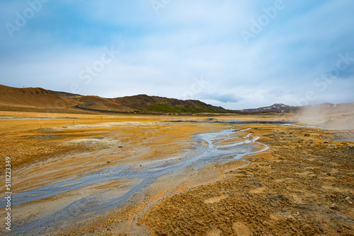 Stream of liquid coming from sulphur bubbling mud gases in active geothermal area in Iceland