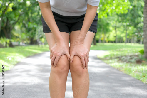 Knee pain .woman stand at park she hand caught at the knee. Having painful feet and stretching muscles fatigue To relieve pain. health concepts