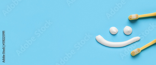 Smile drawn with toothpaste and brushes on light blue background with space for text