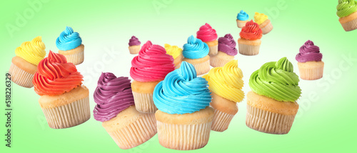 Many flying birthday cupcakes on green background
