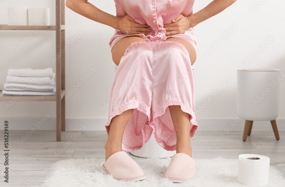 Mature woman with diarrhea sitting on toilet bowl in bathroom Stock Photo |  Adobe Stock