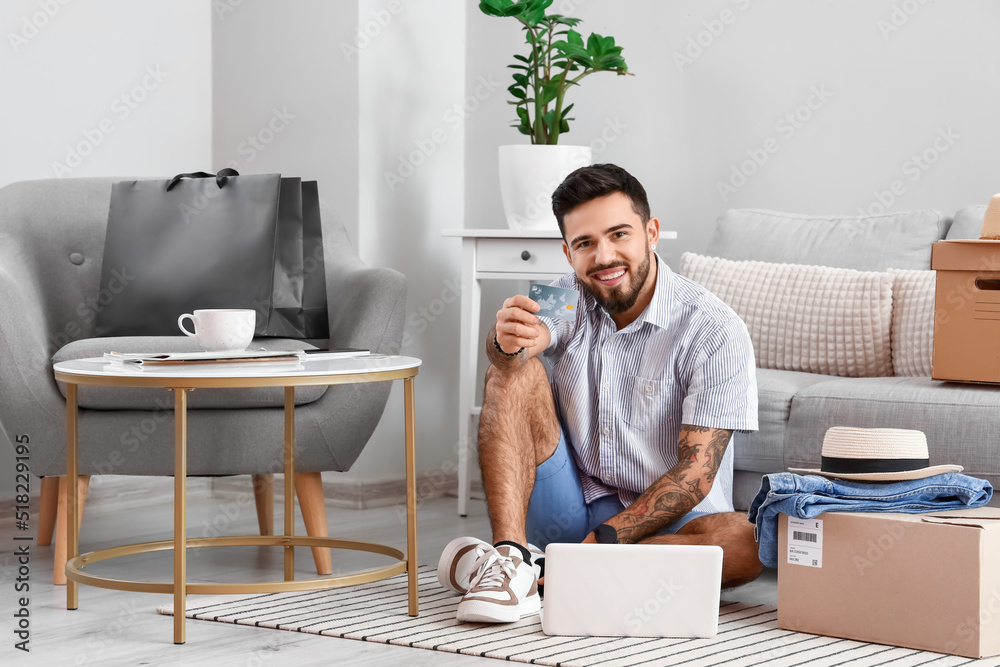 Handsome man with credit card and laptop at home. Online shopping