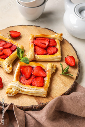Wooden board with strawberry puff pastry on table, closeup