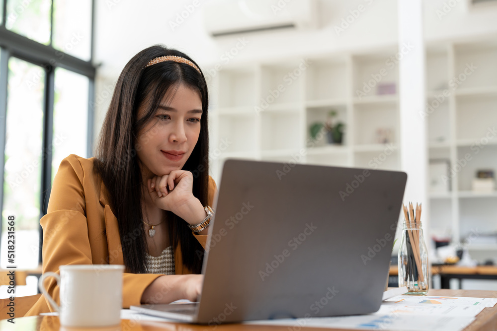Thinking young asian entrepreneur woman in counting profit, on calculator at laptop computer, analyzing benefits, enjoying financial success, job high result, smiling Thinking young asian entrepreneur woman in counting profit, on calculator at laptop computer, analyzing benefits, enjoying financial success, job high result, smiling