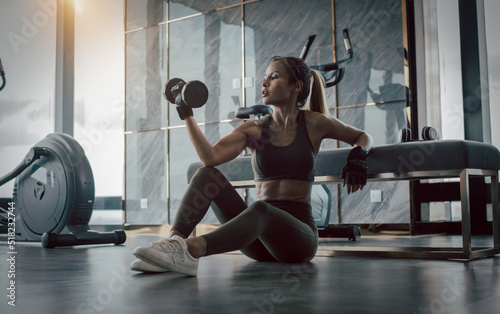 Sport beautiful fitness woman wear sportwear posing under exercise with dumbbell equipment at gym ,she exercise for strong ,make muscle body building and good healthy concept.