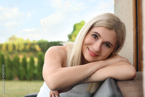 Portrait of beautiful woman sitting near house in yard, space for text