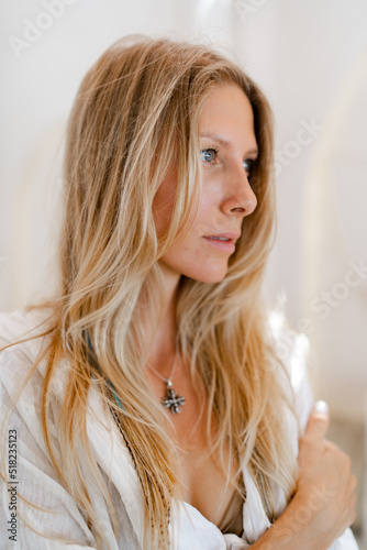 Fashion photo of beautiful blond woman in white summer clothes posing in modern hotel during vacations.