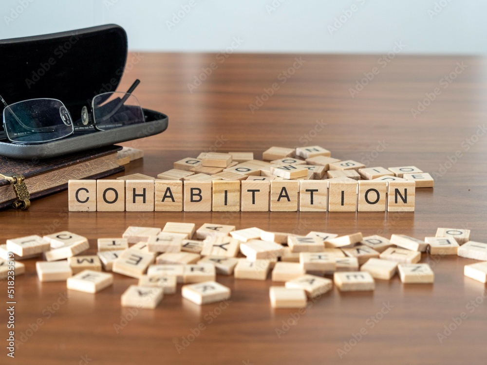 cohabitation word or concept represented by wooden letter tiles on a wooden table with glasses and a book - obrazy, fototapety, plakaty 