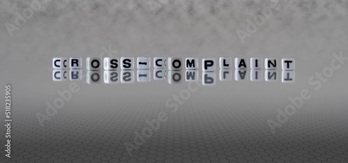 cross complaint word or concept represented by black and white letter cubes on a grey horizon background stretching to infinity