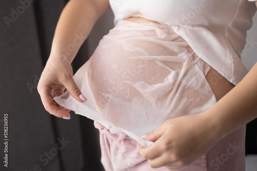 close-up belly of a pregnant woman applying a mask with cream from the appearance of stretch marks, pregnancy, body skin care