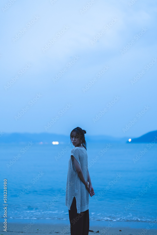 夕暮れの海を散策する女性