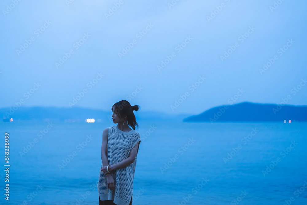 夕暮れの海を散策する女性