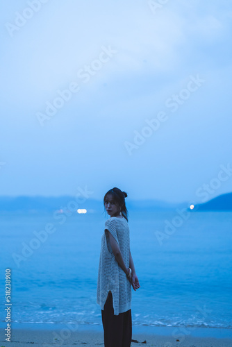 夕暮れの海を散策する女性