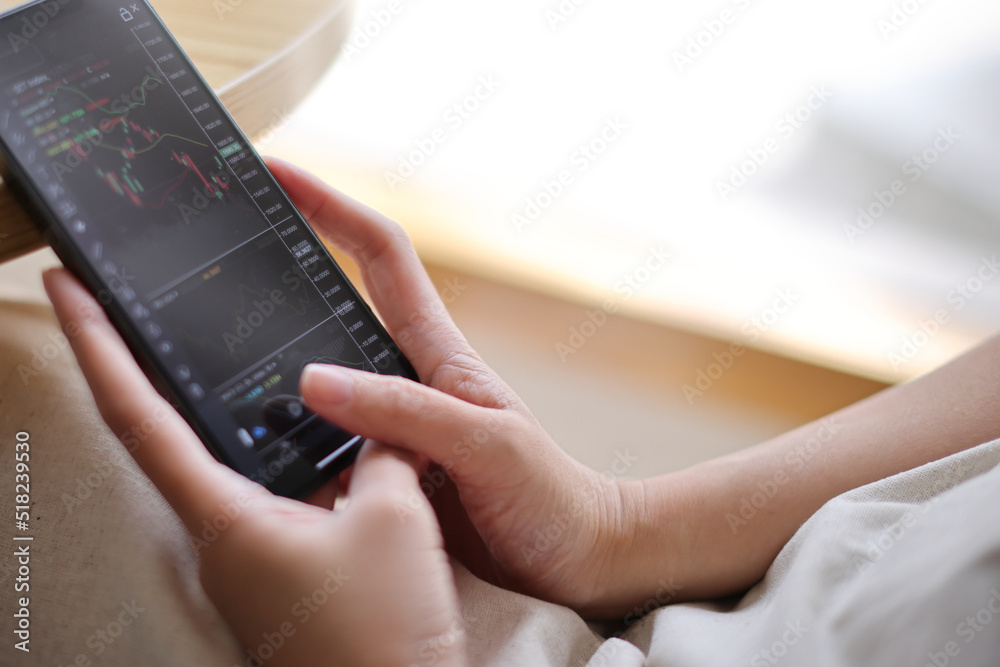 Obraz premium Woman hand using a smartphone for Stock exchange trading online in the coffee shop, business concept