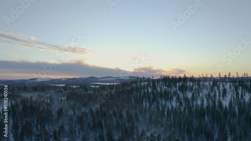 Sunrise aerial view slowly flying over frozen Norbotten Lapland winter forest mountains landscape photo
