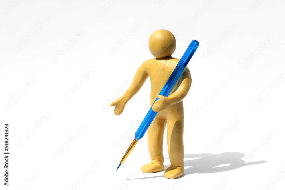 Human figure made of yellow plasticine holding paintbrush on white background. Space for text Human figure made of yellow plasticine holding paintbrush on white background. Space for text