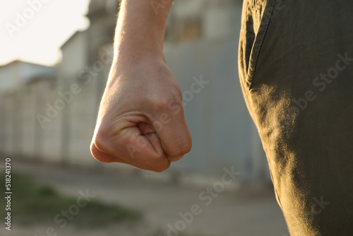 Angry man with clenched fist outdoors, closeup photo